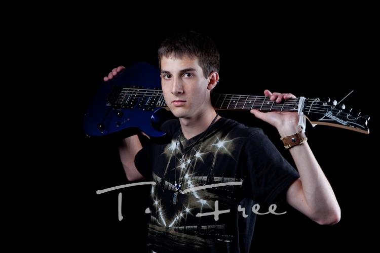 Music artist senior posing with his electric guitar on his shoulders in Omaha.